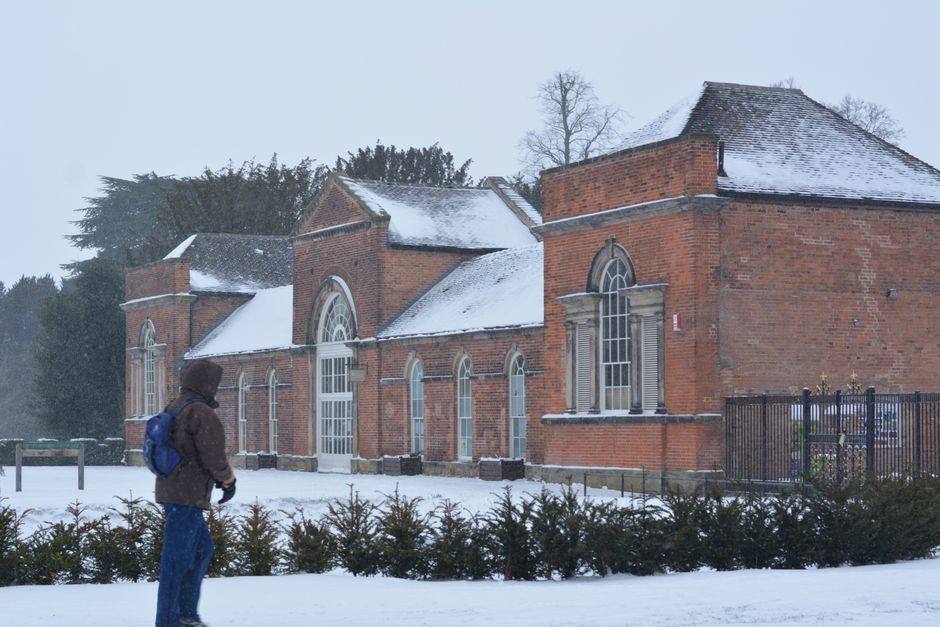 A person walks by a snow-covered historic building during winter.