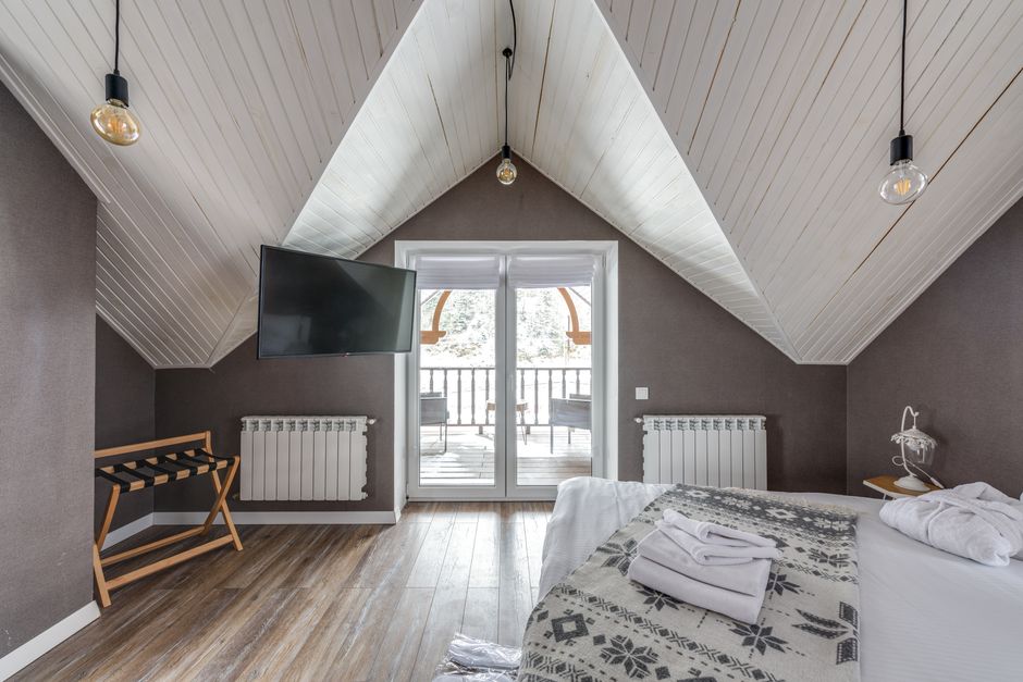 A serene attic bedroom featuring a balcony, TV, and decorative lights.