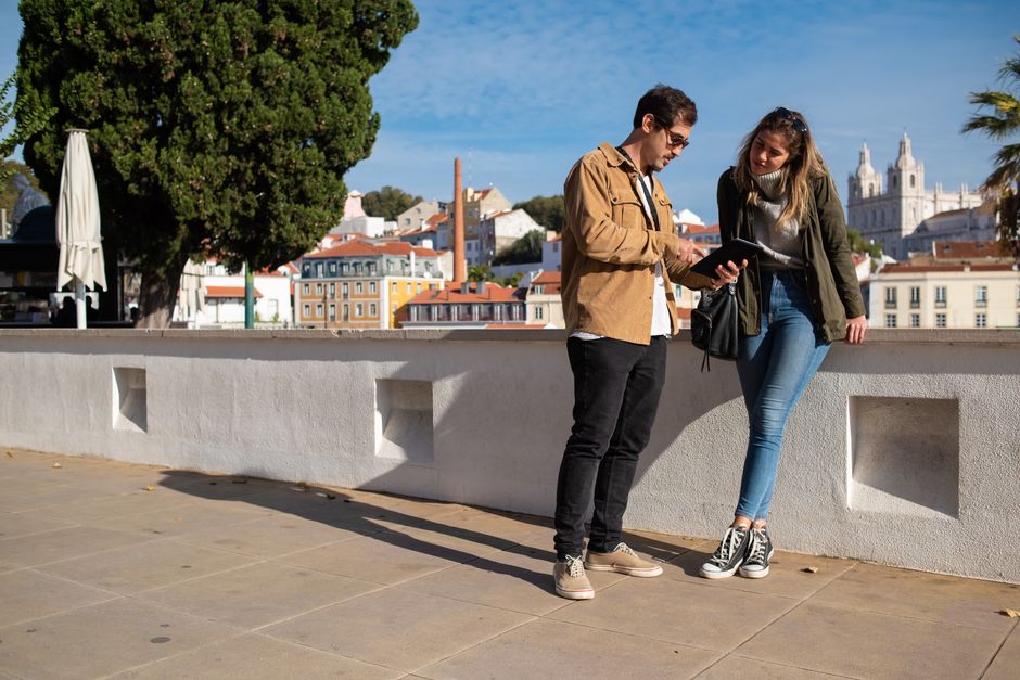 A couple using a tablet in an urban setting with a scenic backdrop, perfect for travel themes.