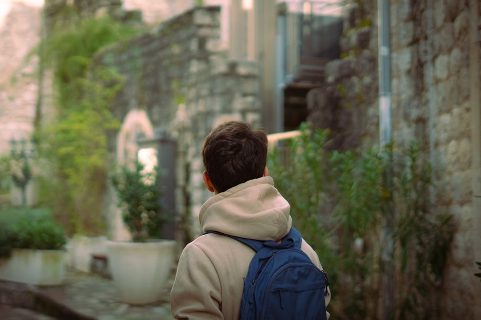 A teenager with a backpack explores a charming historic urban alleyway.