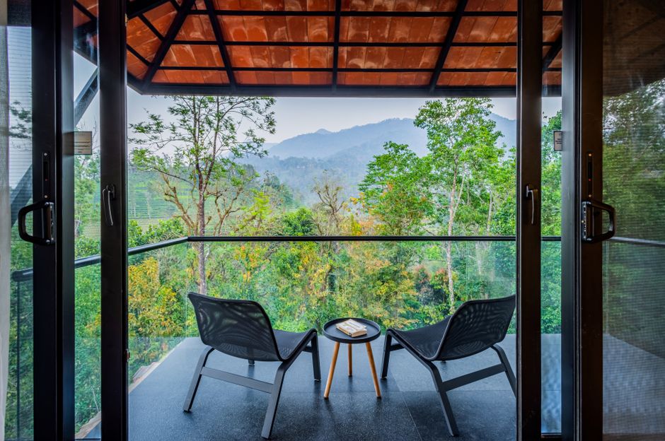 Relaxing balcony with chairs overlooking lush forest and mountains.