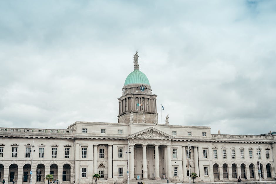 Elegant neoclassical Custom House facade under dramatic cloudy skies in Dublin, Ireland.