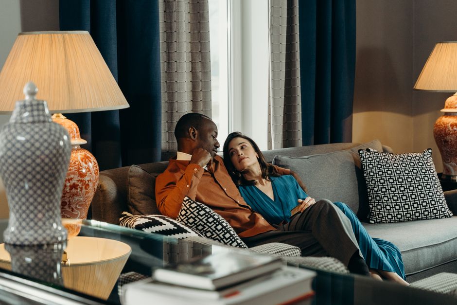 Couple enjoys a relaxing moment on sofa in a modern, warmly lit living room.