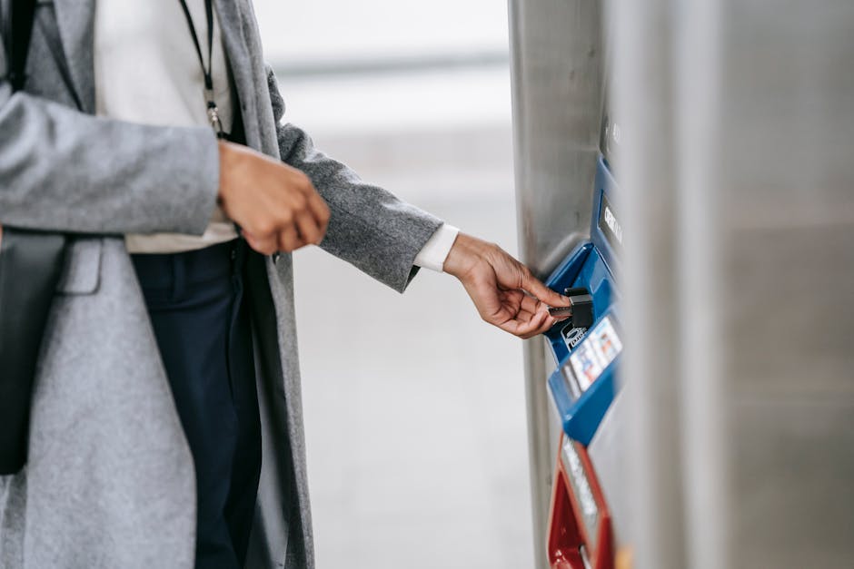 Crop unrecognizable lady in elegant clothes inserting credit card into electronic ticket machine in subway station