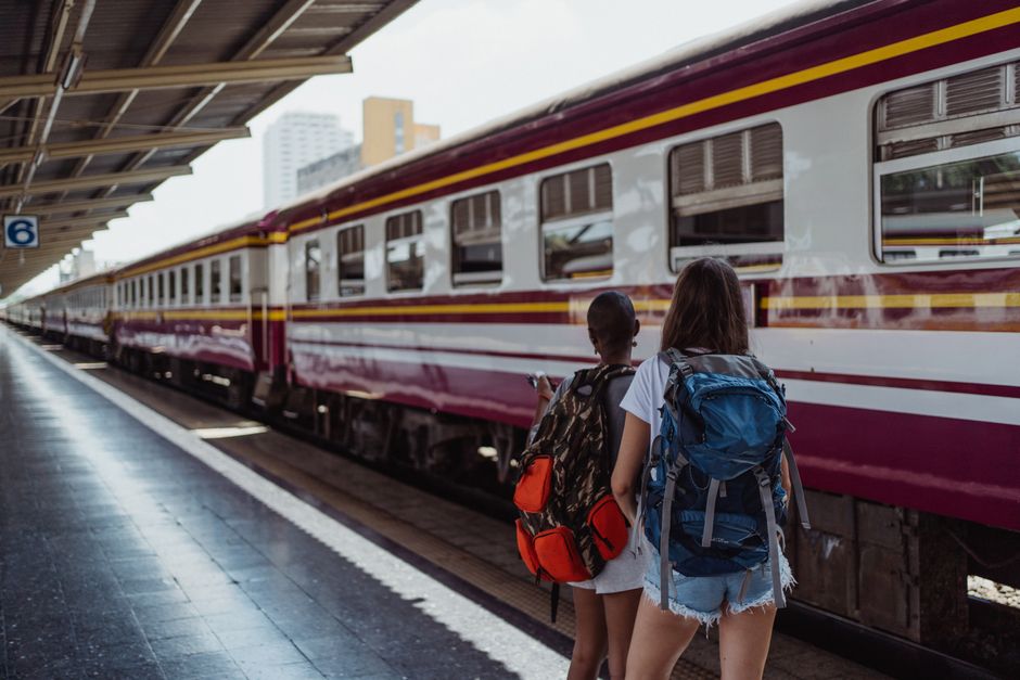 Two women with backpacks waiting at a railway platform, ready for an adventure.