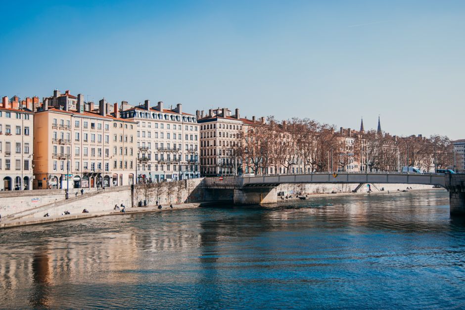 Charming view of Lyon's waterfront architecture reflecting on the river under a clear blue