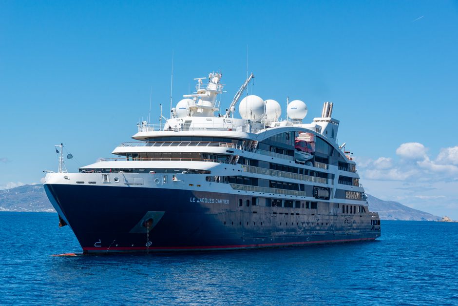 A luxury cruise ship sailing on open blue waters under a clear sky.