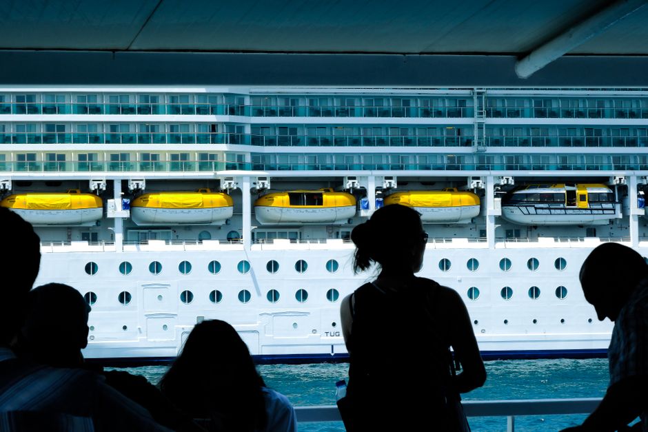 Silhouettes of people observing a large cruise ship from a dock in Türkiye.