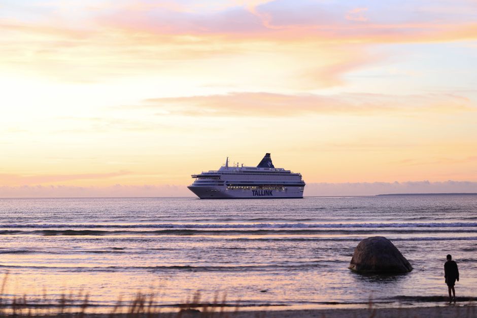 A cruise ship sails on tranquil waters during a stunning sunset, creating a serene travel scene.