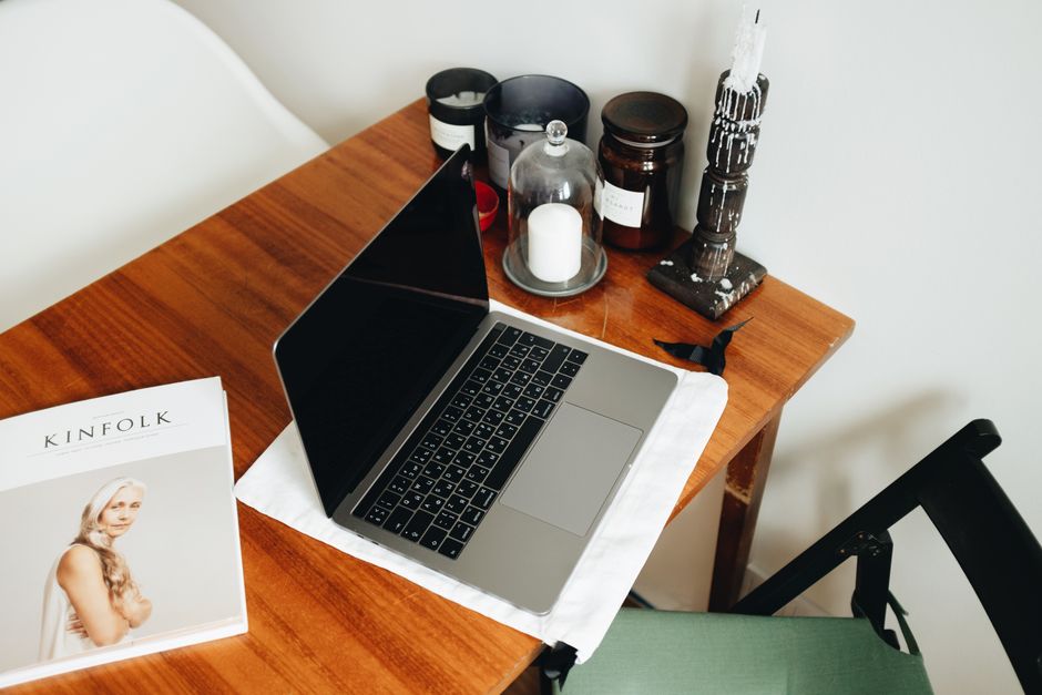 From above of opened laptop and art magazine with various black candles placed on wooden table in modern workplace