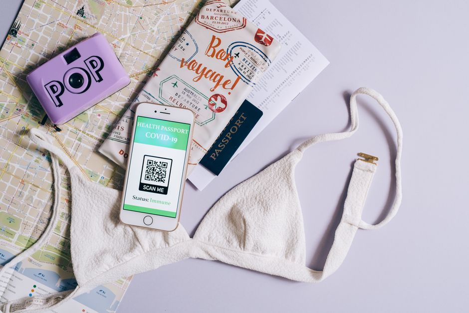 Flat lay of travel items including a COVID health passport, map, and bra, highlighting travel readiness.