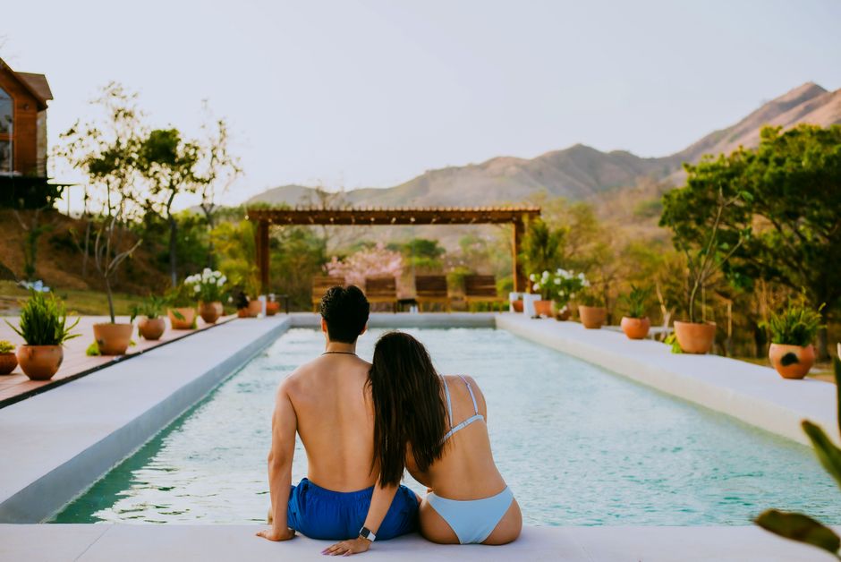 A couple enjoys a relaxing summer day by the pool at a scenic resort.
