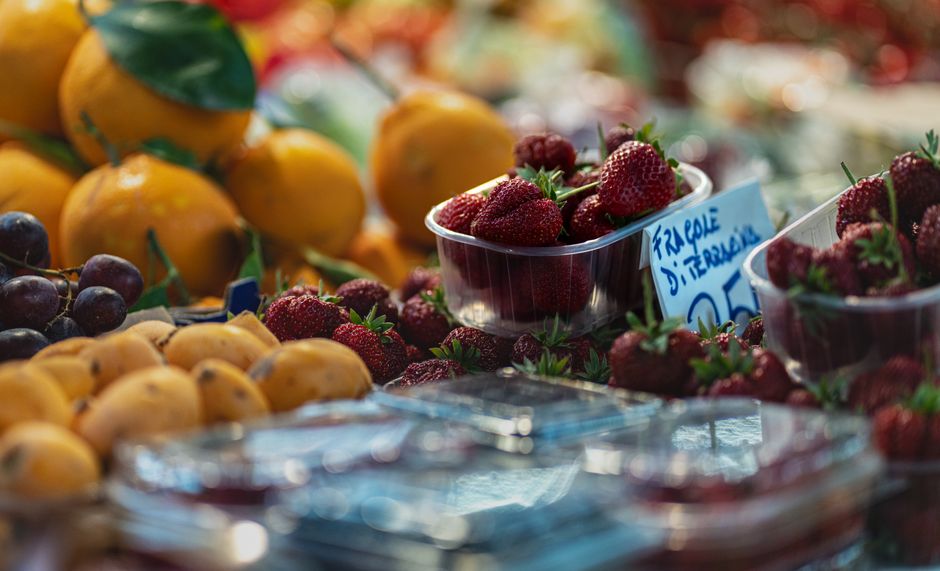 Fresh fruits including strawberries and citrus at an outdoor market stall.