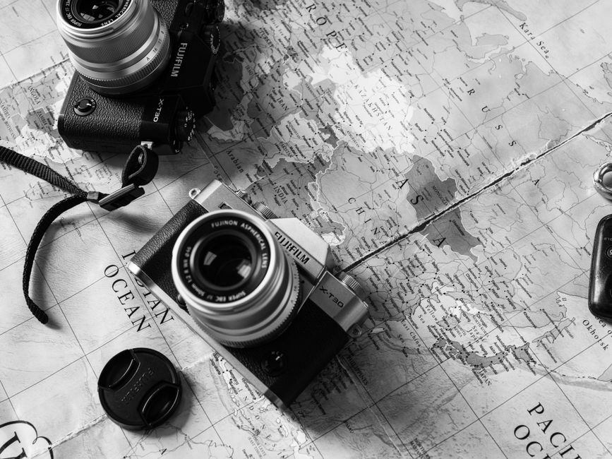 Two vintage cameras placed on a world map, highlighting travel themes.