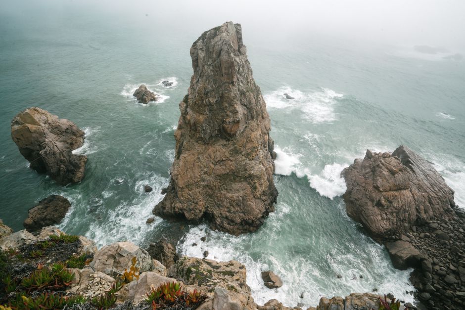 From above of picturesque scenery of foamy sea waves running through rough cliffs