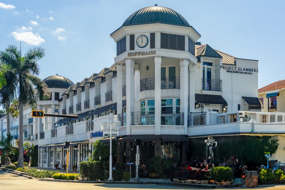 Elegant architecture at a shopping center in Naples, Florida with palm trees and clear skies.