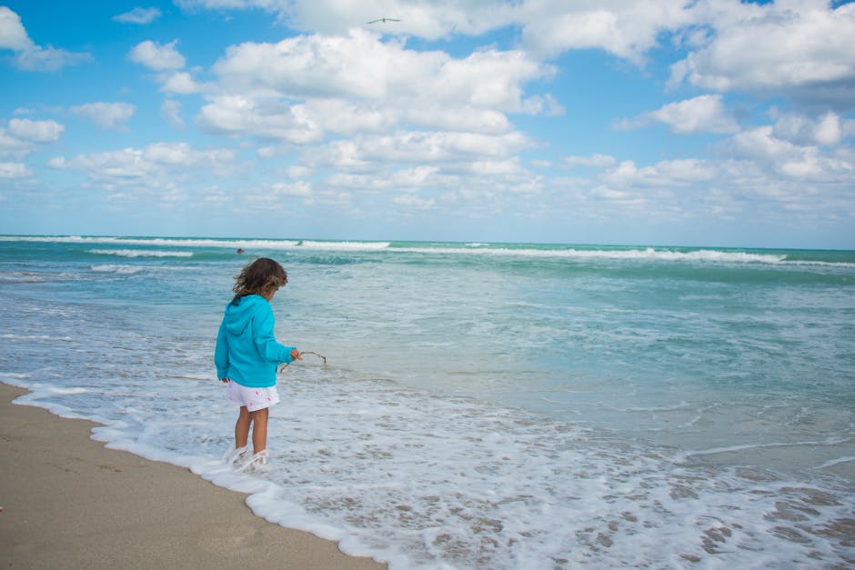 Young girl enjoys playing with water at the beach on a sunny day.