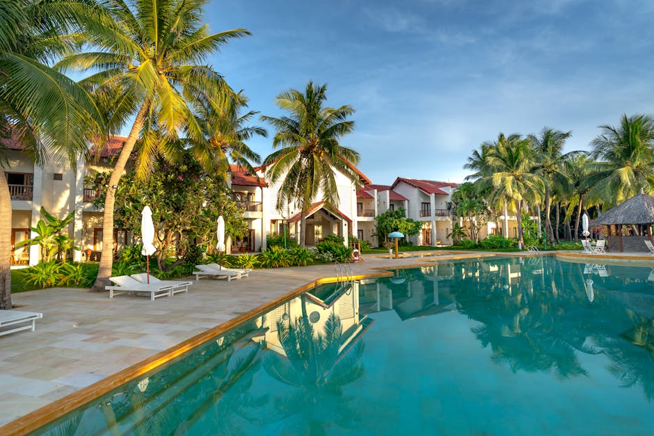 Luxury resort poolside view with palm trees, offering a tropical and serene escape.
