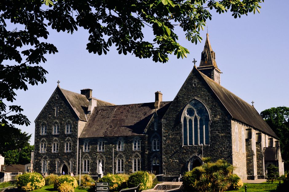 Beautiful stone church in Killarney, Ireland, under clear blue skies.