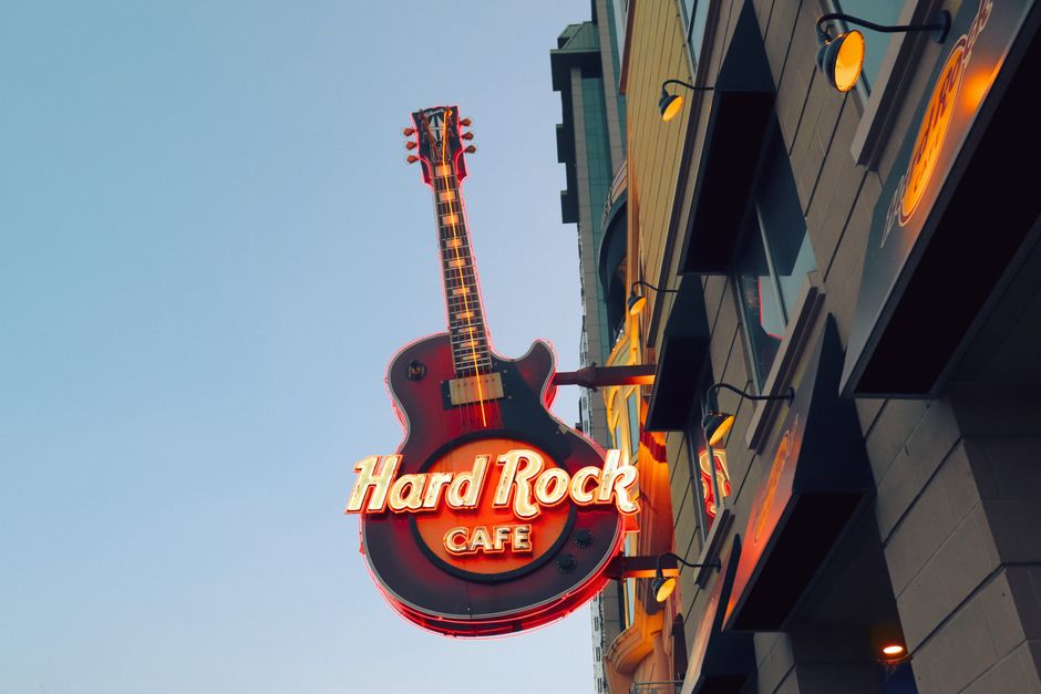Vibrant neon guitar sign of Hard Rock Cafe in Ontario against clear sky.