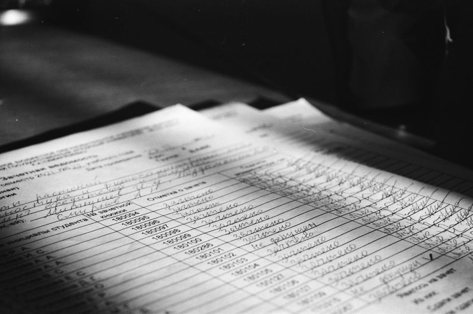 Close-up grayscale photo of a handwritten document with visible text and shadows.