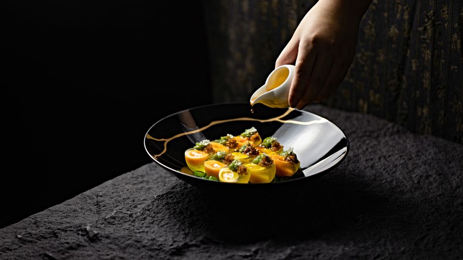A gourmet seafood dish elegantly plated with sauce being poured over it.