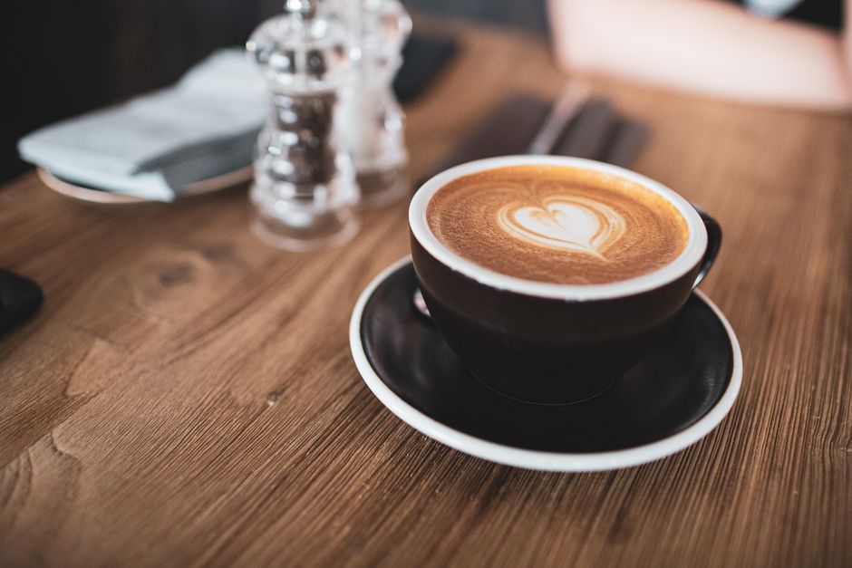 Warm latte with heart-shaped art in a cozy wooden cafe setting.