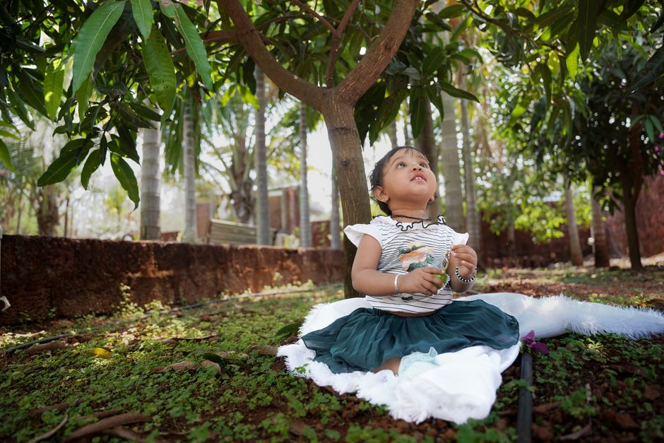A young girl sits happily under a tree, enjoying a peaceful moment in nature.