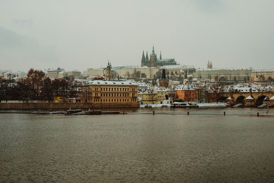 Beautiful winter view of Prague Castle and Charles Bridge after snowfall, showcasing historical architecture and culture.