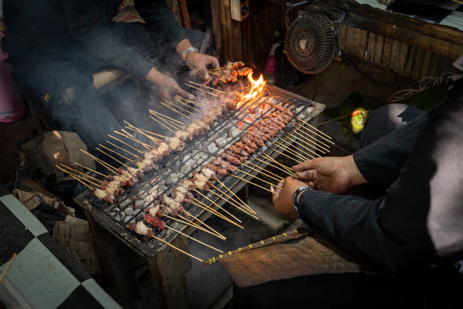 Traditional Indonesian street food with delicious meat skewers grilling over charcoal.