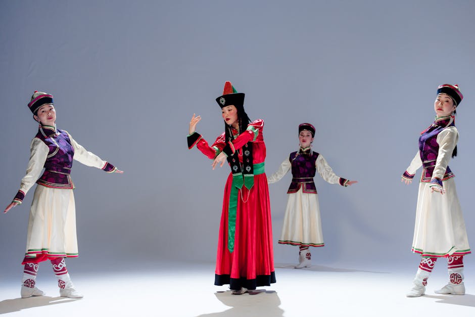 Four women in traditional Asian costumes performing a cultural dance indoors with vibrant movements and colorful dresses.