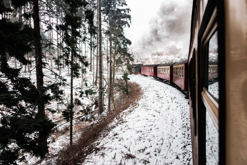 A steam train travels through a snowy forest, offering a nostalgic winter journey.