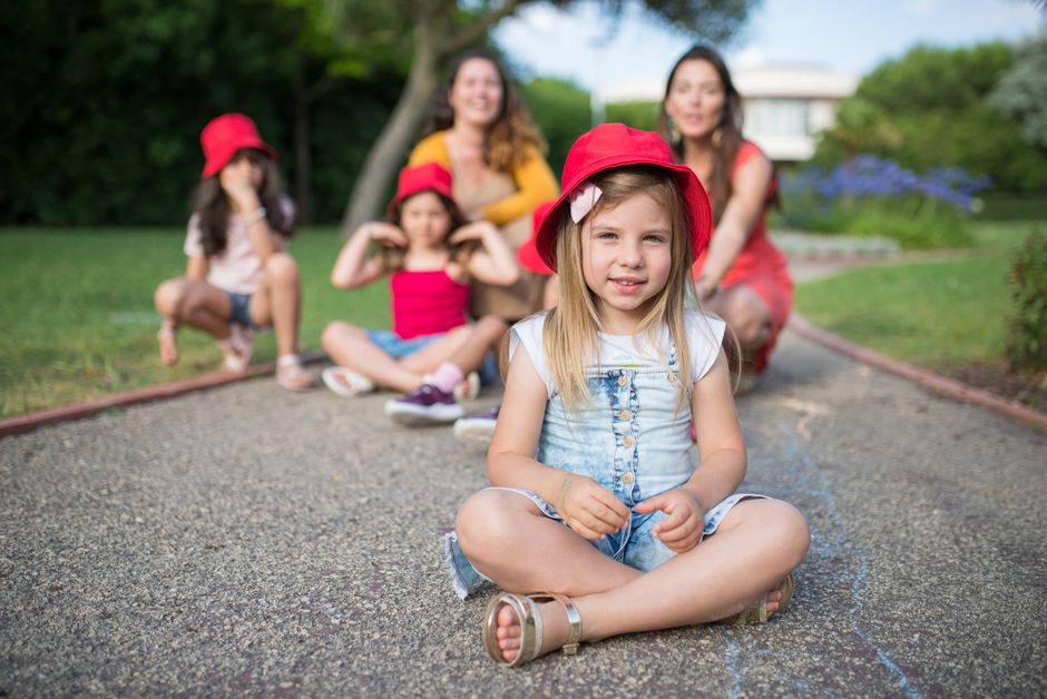 A group of smiling children wearing red hats enjoy a playful day outdoors in Portugal.
