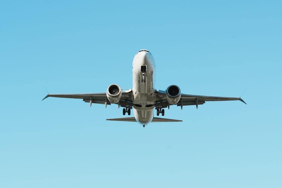 View of a commercial airplane flying with a clear blue sky background, focusing on travel and aviation.