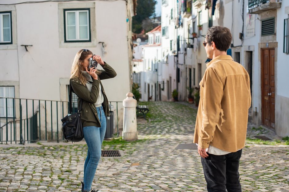 A man and woman capturing moments on a picturesque cobblestone street, ideal for travel and urban photography.