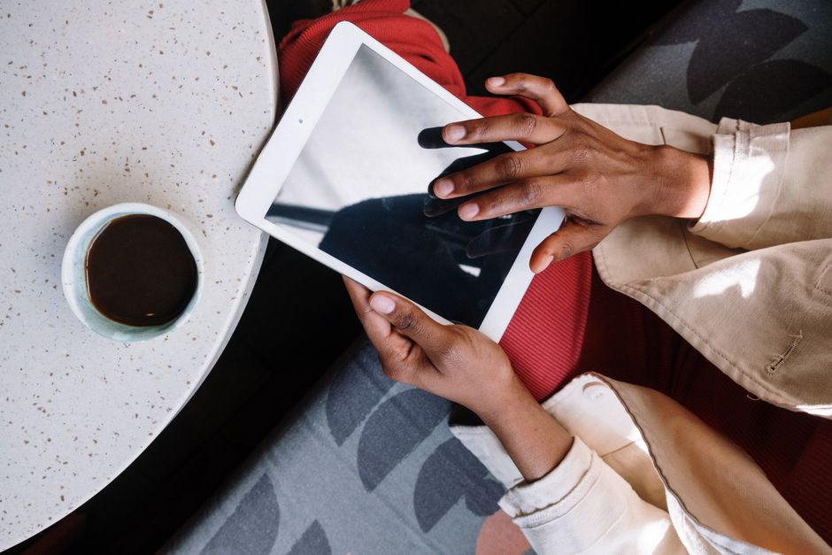 Hands interacting with tablet in a café setting, showcasing technology and lifestyle blend.