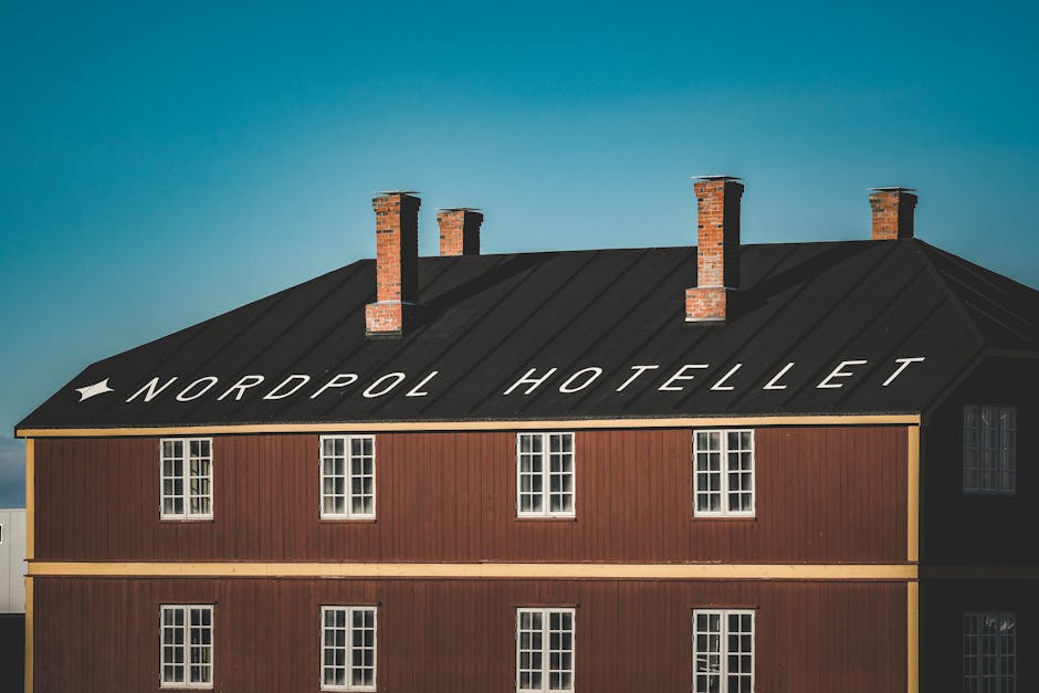 A vintage red building with the text 'Nordpol Hotellet' on the roof, featuring multiple chimneys.
